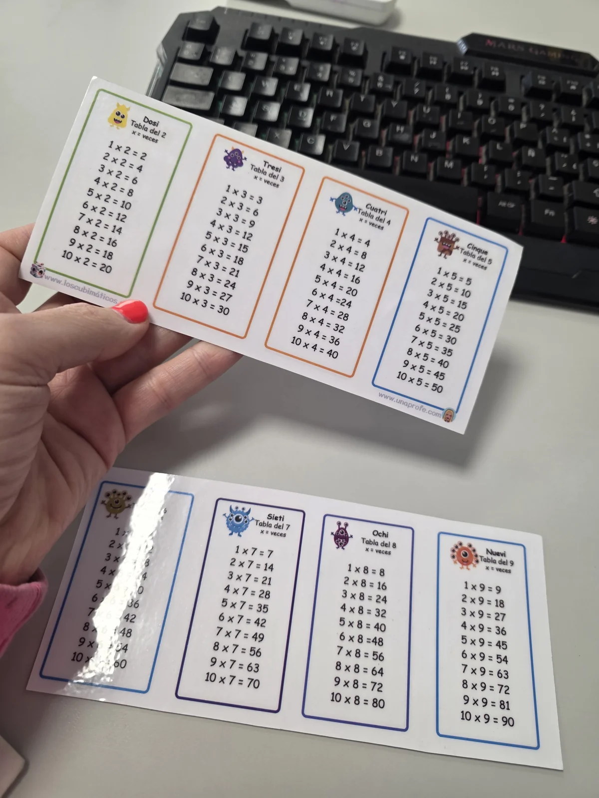 Tarjeta pequeña con las tablas del 2 al 5 en la mano y la cara del 6 al 9 sobre la mesa