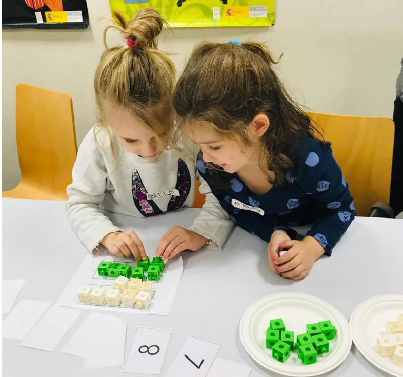 Dos niñas construyen una representación matemática con cubos encajables